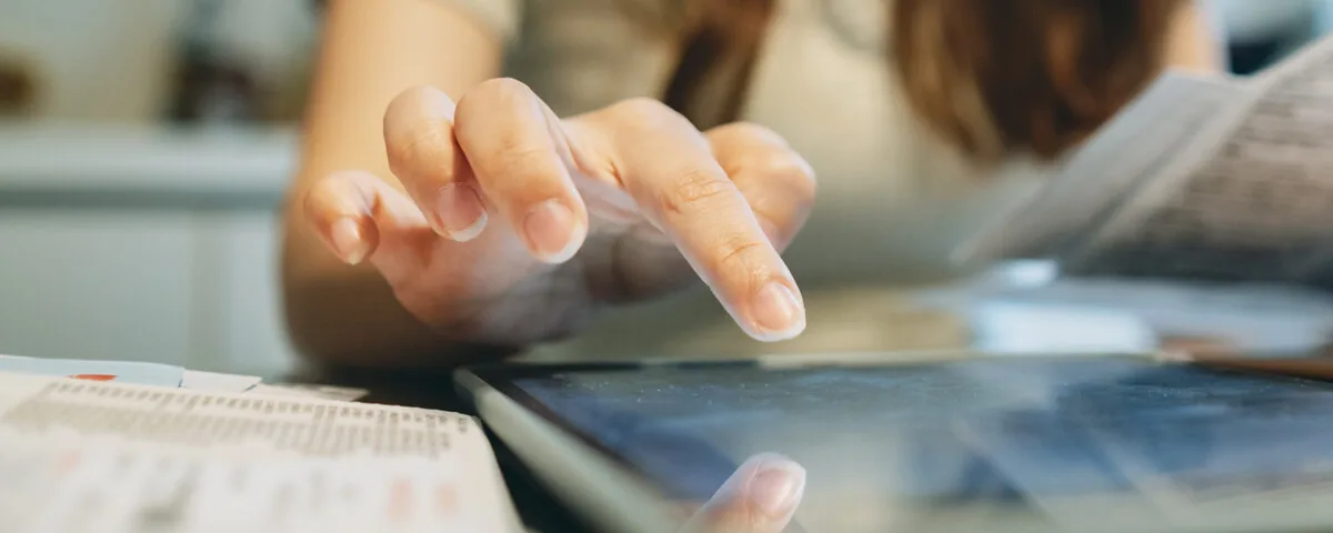 Hand tippt auf ein Tablet, daneben eine Stromrechnung und eine Verbrauchsübersicht