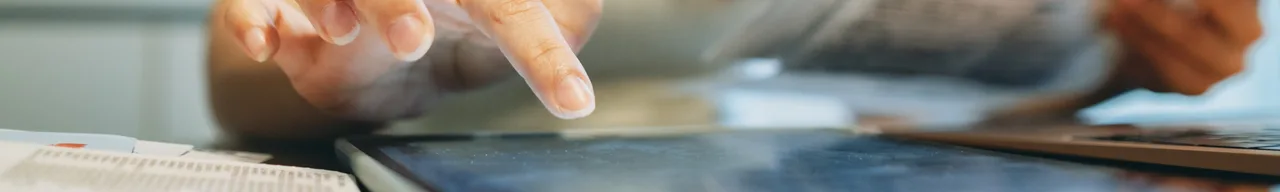 Hand tippt auf ein Tablet, daneben eine Stromrechnung und eine Verbrauchsübersicht